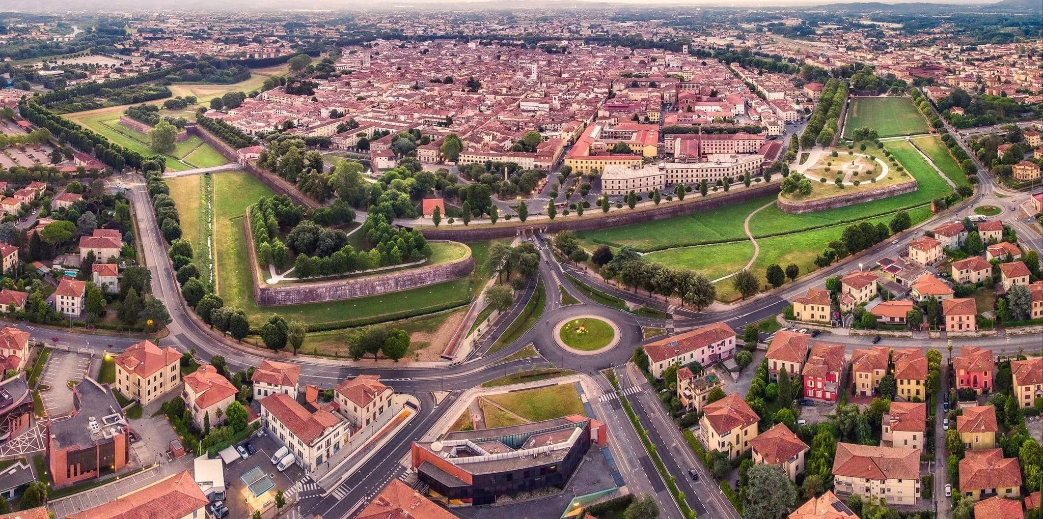 Fotografia reale di Lucca vista dall’alto, con le Mura, gli alberi e le case del centro storico